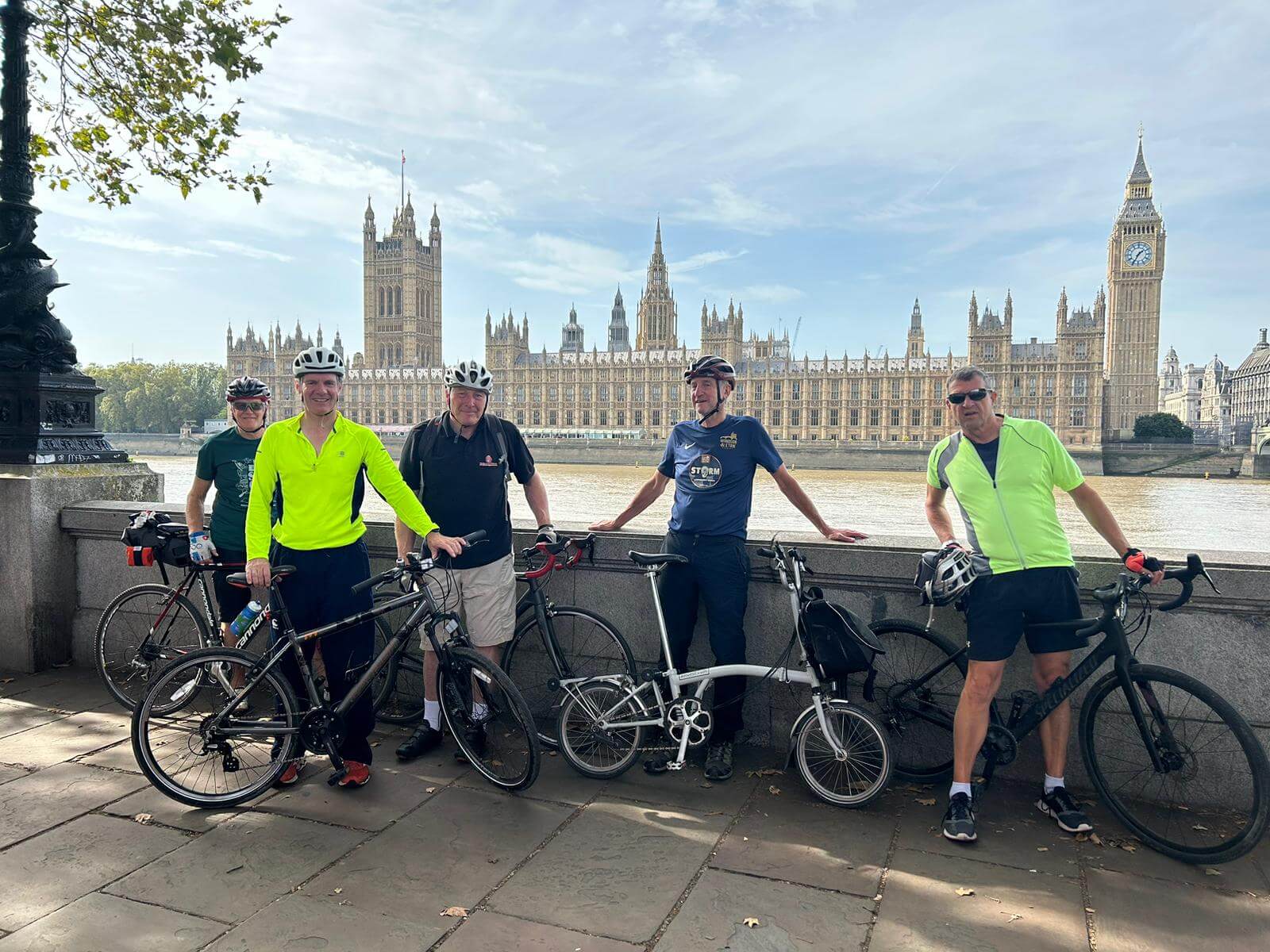 Cyclists stop to admire the view of Palace of Westminster along the Thames.